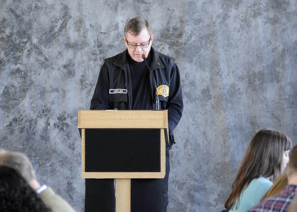 Mike Neil in chaplain uniform bowed in prayer at podium
