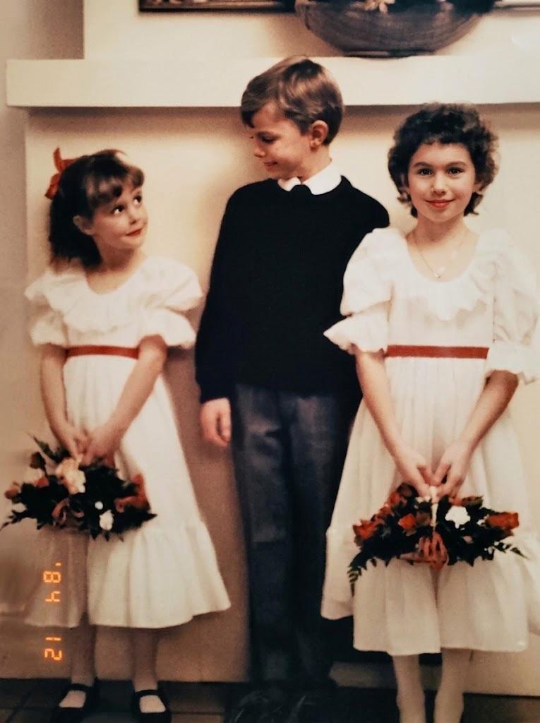 Susanne and siblings dressed as flower girls and ring bearer at a wedding