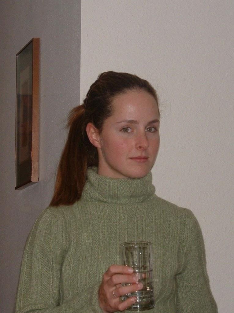 Susanne in a green turtleneck sweater holding a glass